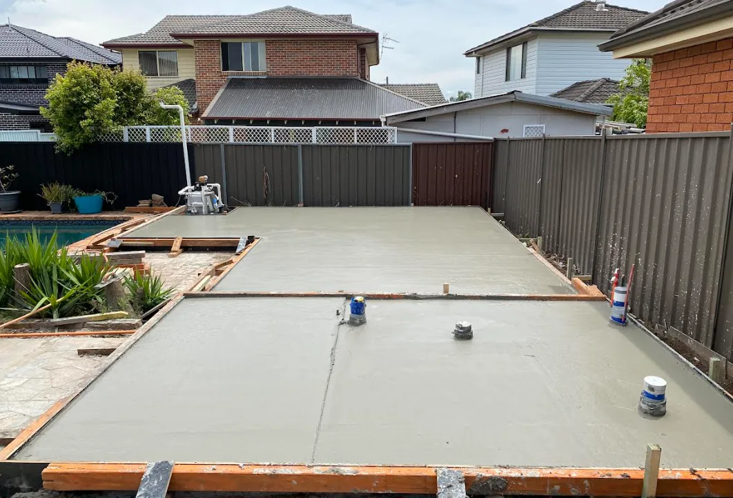 Cured concrete slab in a landscaped rear yard between timber fences