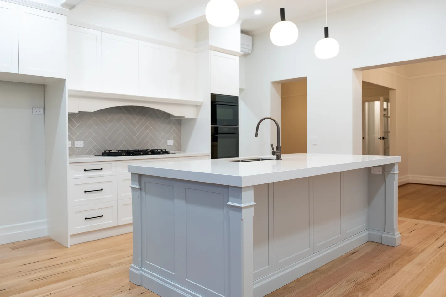 Upgraded kitchen with shaker cabinetry, stone island bench, pendant lights and herringbone splashback
